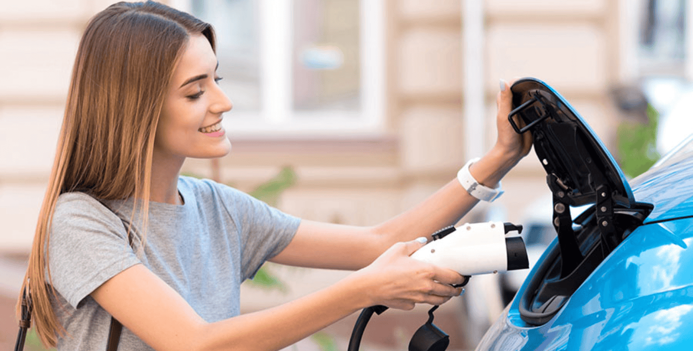 Femme branchant un cordon de recharge à son véhicule électrique