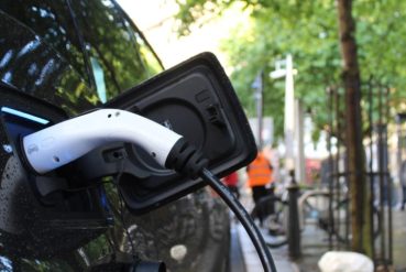 Cordon de recharge branché sur une voiture électrique stationnée sur une place