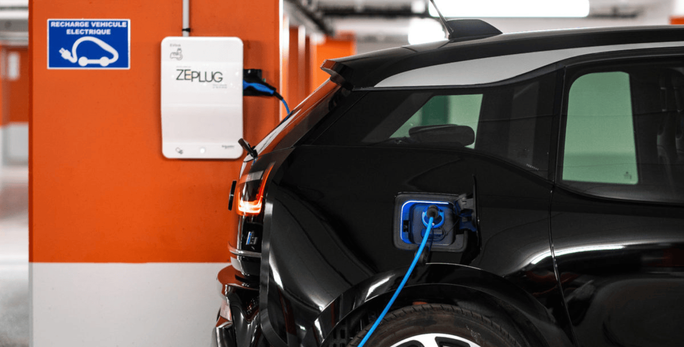 Voiture électrique citadine se rechargeant dans un parking souterrain par une borne de recharge Zeplug