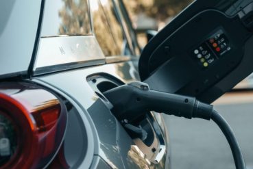 Voiture électrique branchée par un cordon de recharge dans un parking extérieur