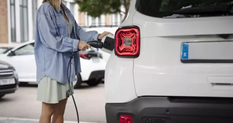 Femme rechargeant son véhicule électrique dans la rue