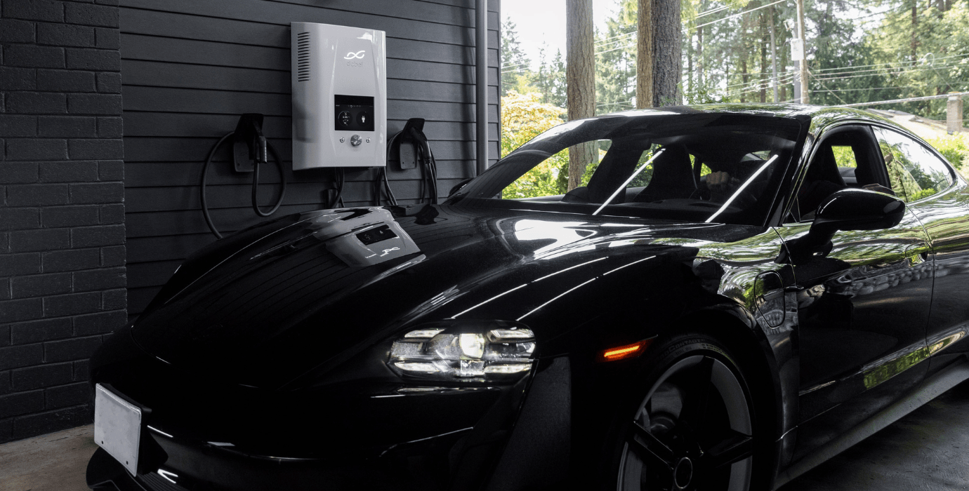 Voiture noire électrique stationnée près d'une borne de recharge blanche dans un parking privé