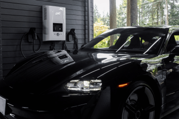 Voiture noire électrique stationnée près d'une borne de recharge blanche dans un parking privé