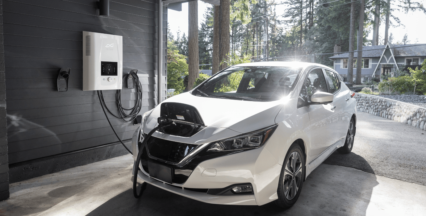 Voiture électrique blanche branchée à une borne de recharge dans un parking privé