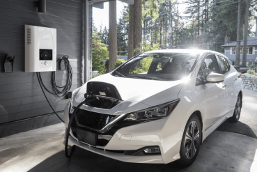 Voiture électrique blanche branchée à une borne de recharge dans un parking privé