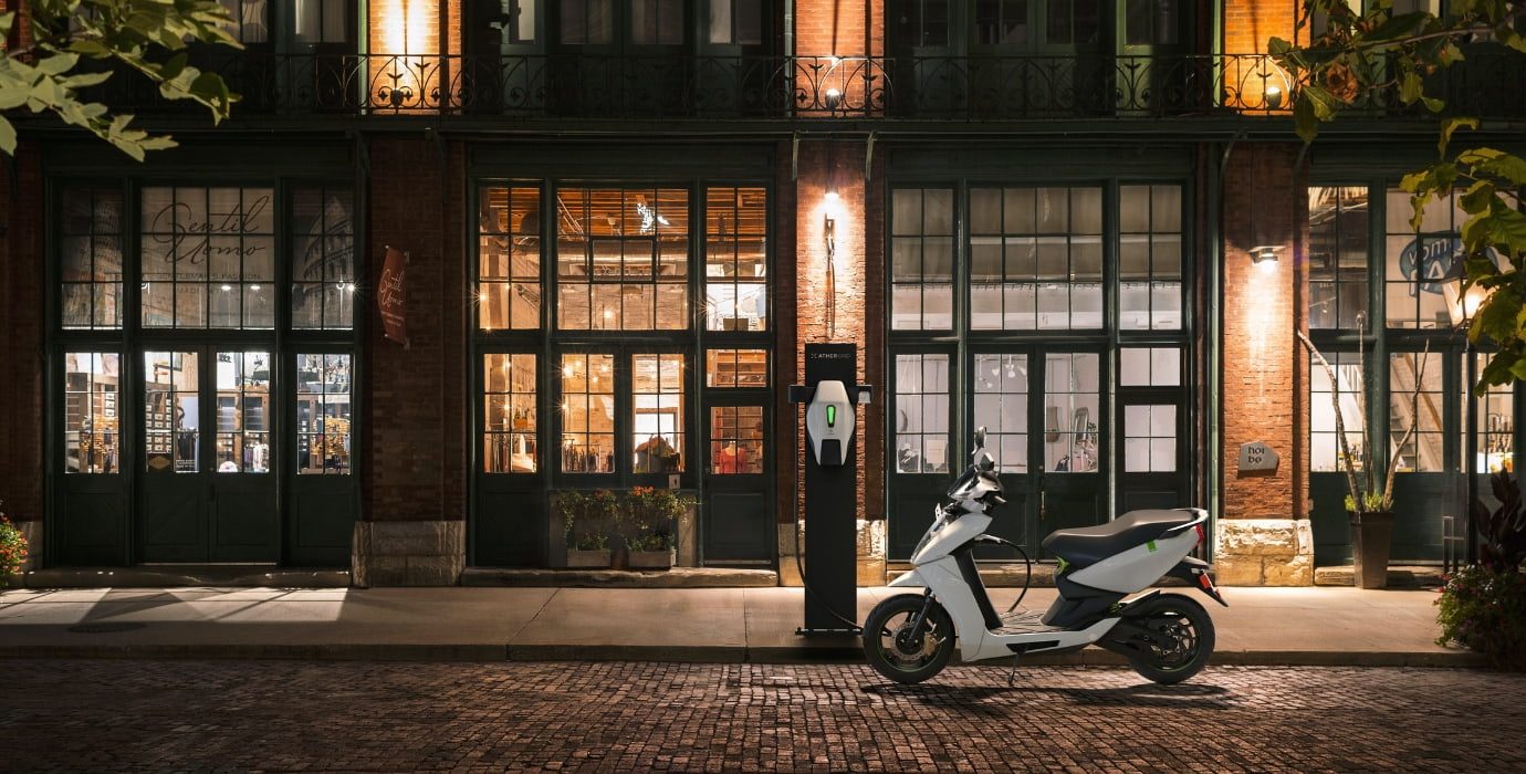 Scooter électrique se recharge à une borne à l'extérieur en pleine soirée