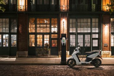 Scooter électrique se recharge à une borne à l'extérieur en pleine soirée