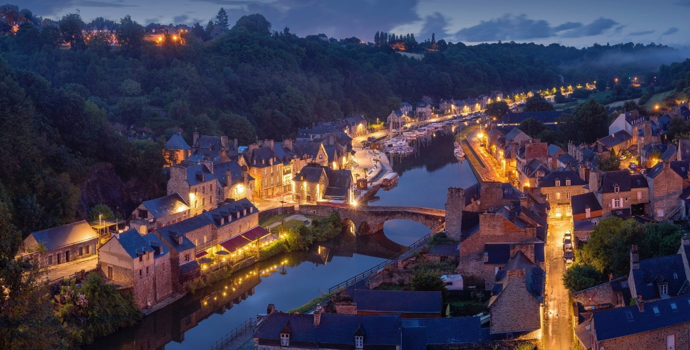 Ville fluviale médiévale illuminée par des lampadaires un soir d'été
