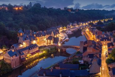 Ville fluviale médiévale illuminée par des lampadaires un soir d'été