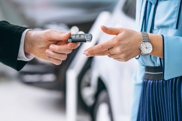 La main d'un homme donnant une clé de voiture à une femme avec une montre au poignet