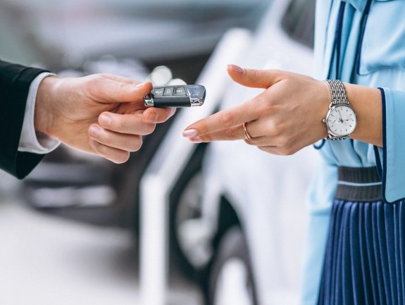 La main d'un homme donnant une clé de voiture à une femme avec une montre au poignet