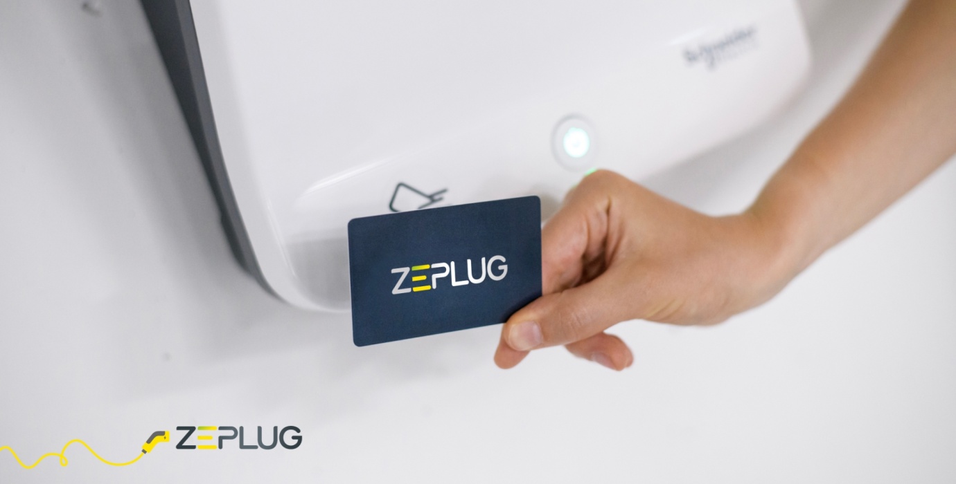 Photo en gros plan d'un badge Zeplug, devant une borne de recharge.
