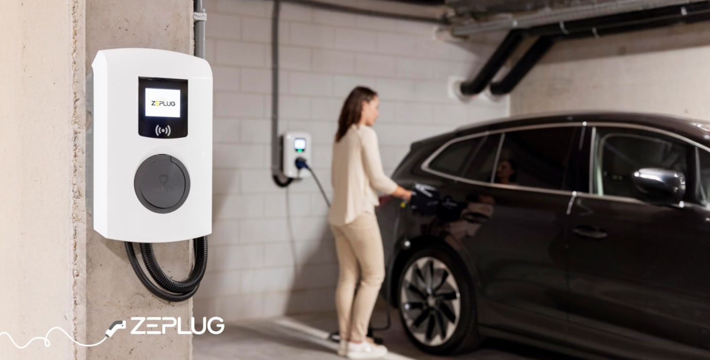 Borne de recharge dans un parking sous terrain. Femme branche son véhicule en arrière plan.
