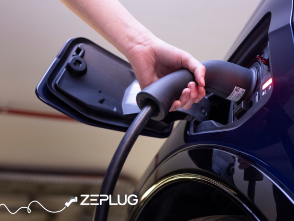 Main qui branche un câble de recharge dans la prise de recharge d'une voiture électrique.